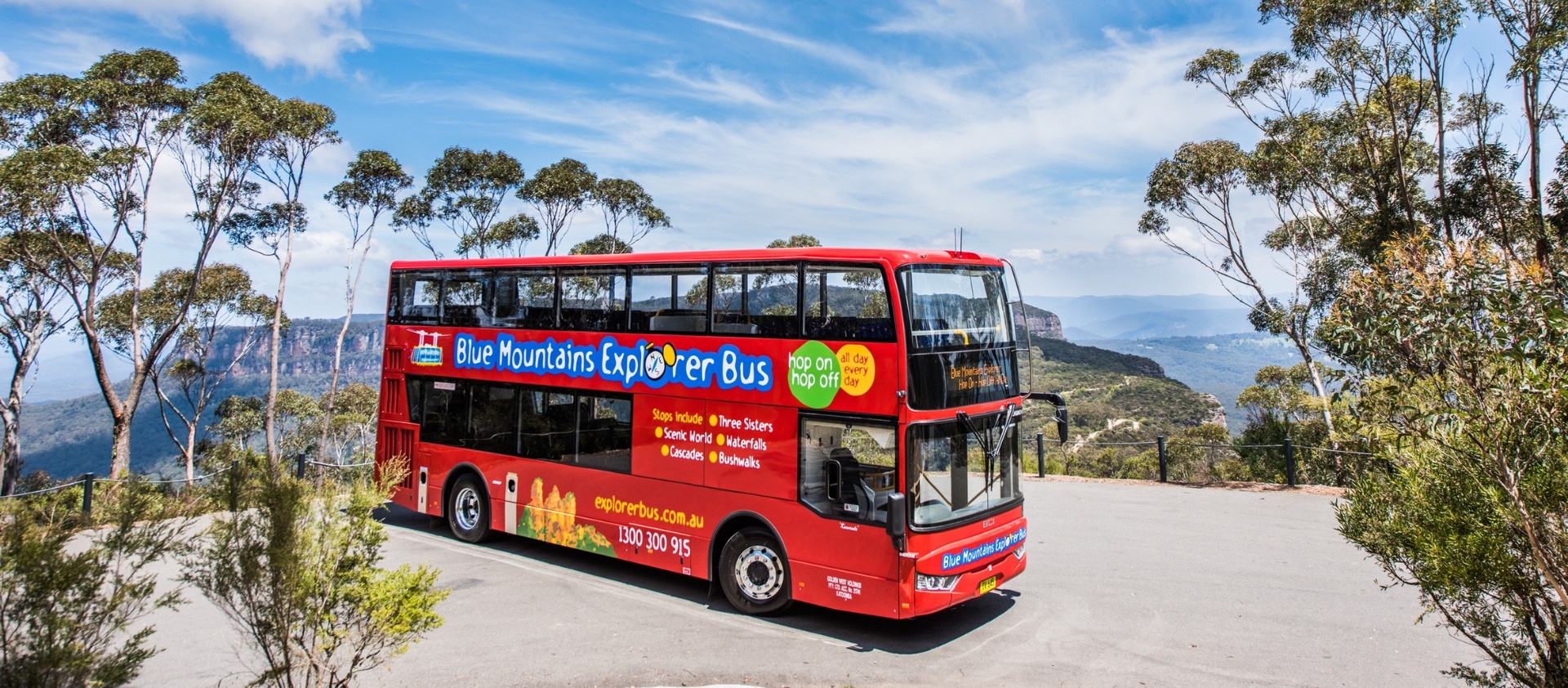 Blue Mountains Explorer Bus at a scenic lookout with gum trees and distant escarpment